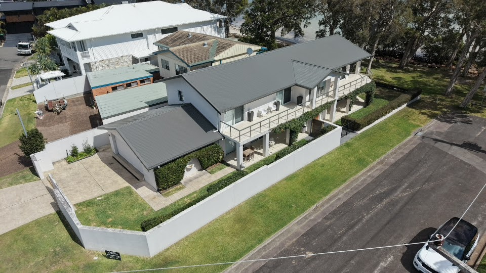 Aerial view of a large waterfront home with a newly finished mid grey roof