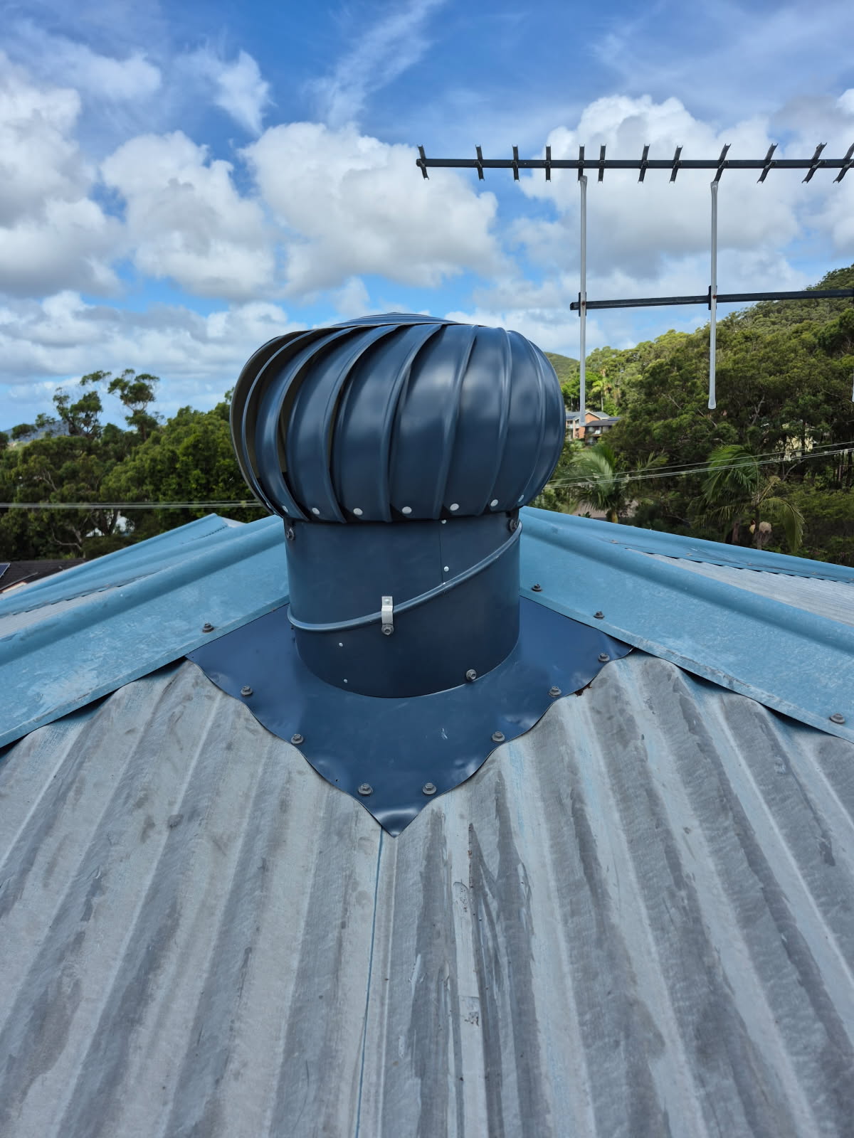 Newly installed charcoal roof ventilator flashed into a corrugated roof