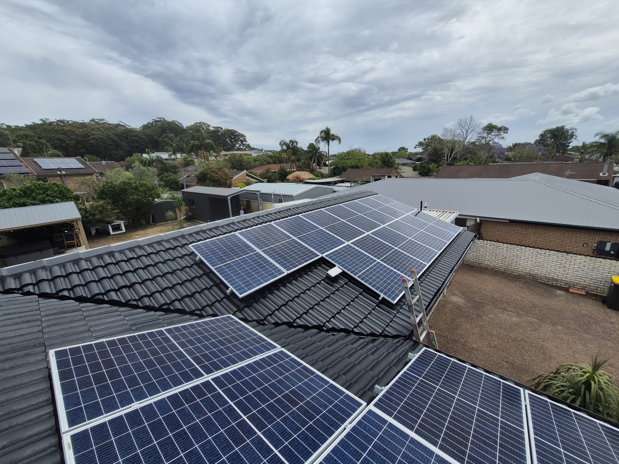 Solar panels sitting on a restored dark tile roof
