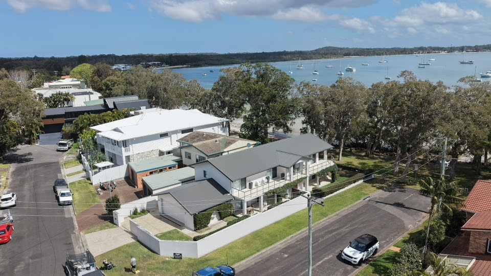 Aerial view of a Port Stephens home with a freshly finished roof, the bay and moored yachts behind