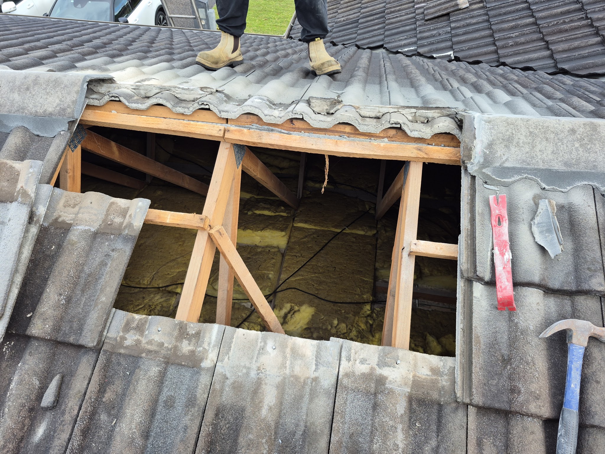 Roof tiles lifted out mid repair, exposing the rafters and insulation beneath
